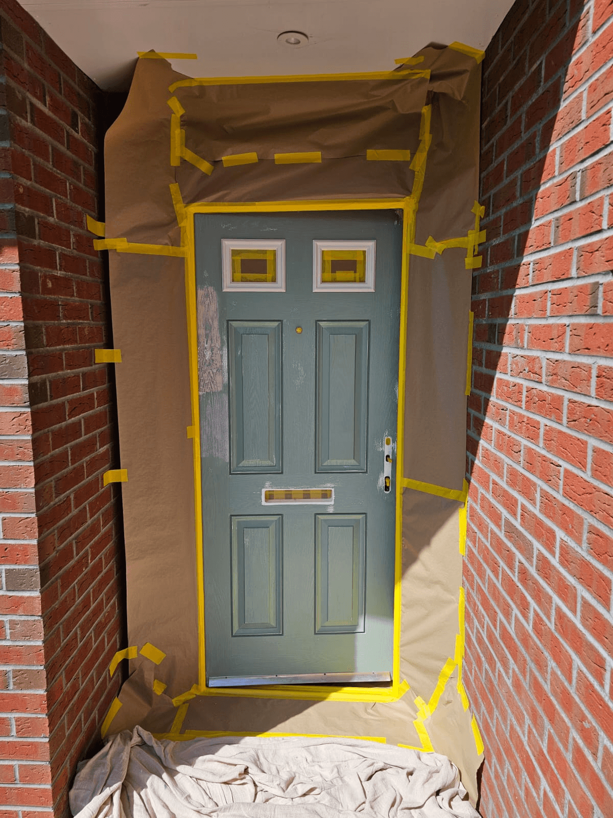 UPVC door spraying Sheffield — sage green front door in progress with masking
